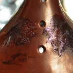 Close-up of a brown ceramic instrument with black markings and two finger holes