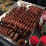 A tray of glazed donuts, some with chocolate frosting.