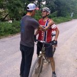 Finish!A person in cycling gear on a bicycle is being greeted by another person