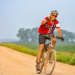 Cyclist on dirt road waves