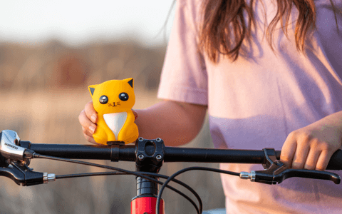 Child standing next to bicycle with hand on the kitty shaped horn.