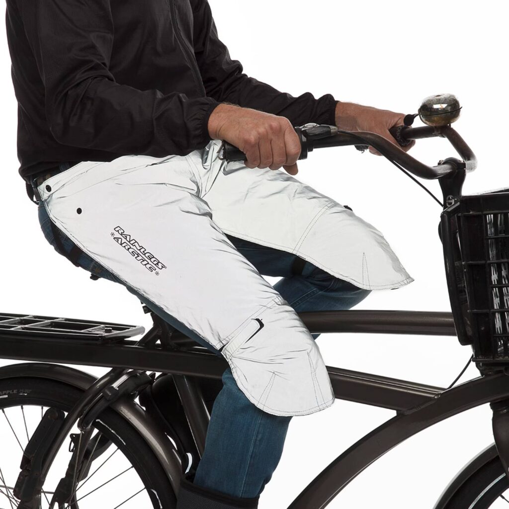 A person riding a bike while modeling Rainlegs reflective chaps. 