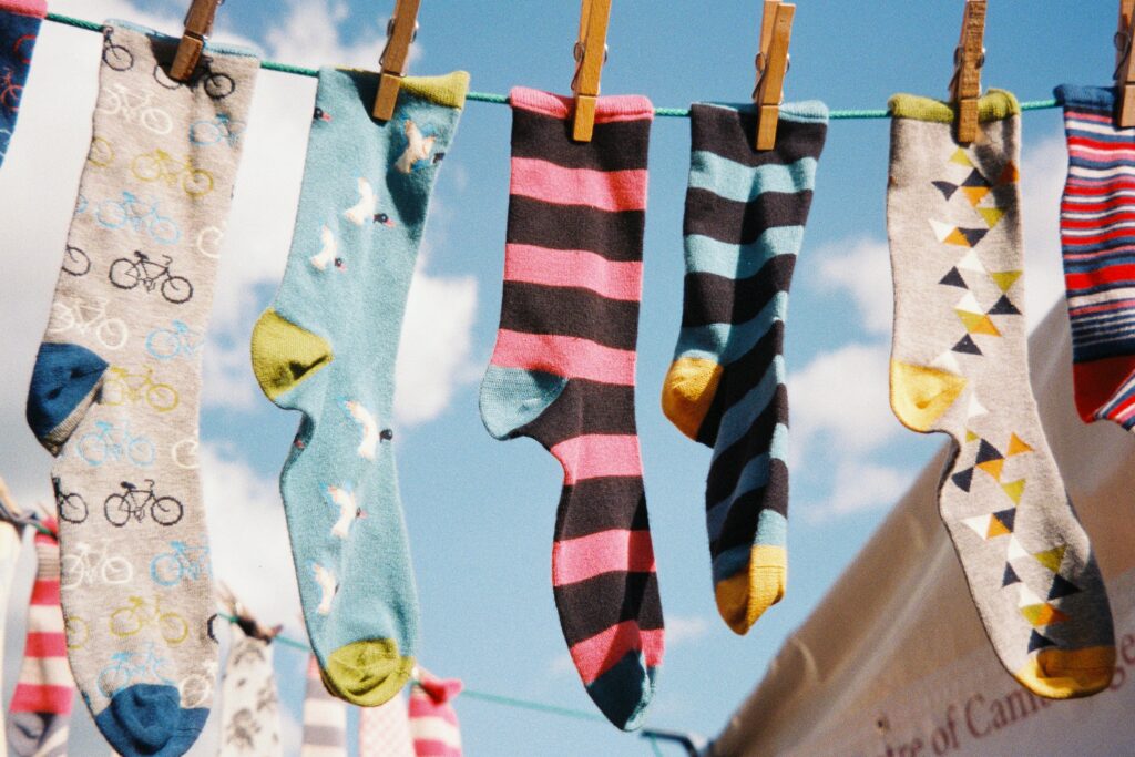 Various socks pinned to a clothesline outdoors.